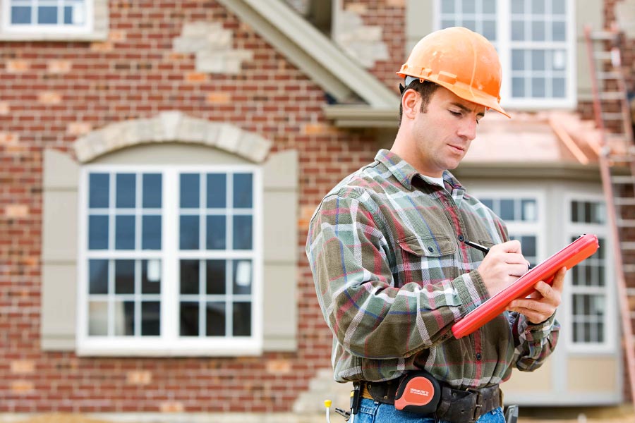 An inspector takes notes on a house in the Lockhart TX real estate market