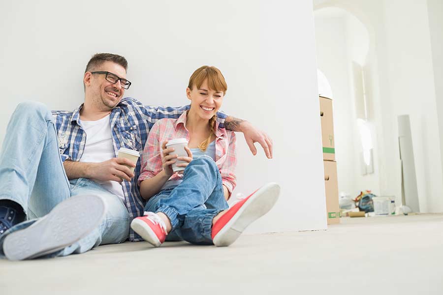 cheerful couple with coffee cups in new house