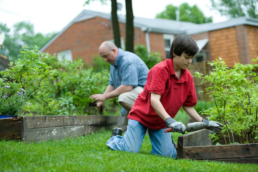 Dad and son working in a garden at their new Lockhart house