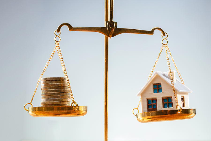 Scale with money and houses for sale, representing real estate in Lockhart