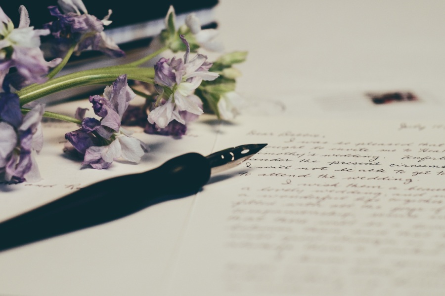 handwritten letter for a Houses and Homes for Sale in Lockhart, Tx with flowers and a pen sitting on it closeup