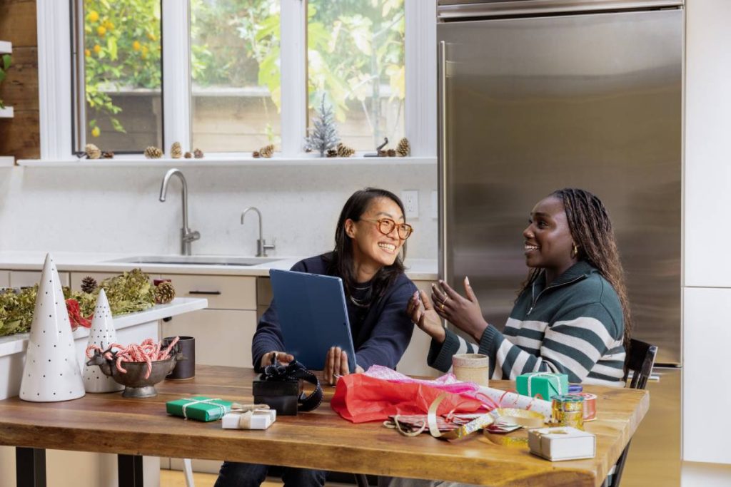 2 roommates talking and laughing while sitting at a dining room table