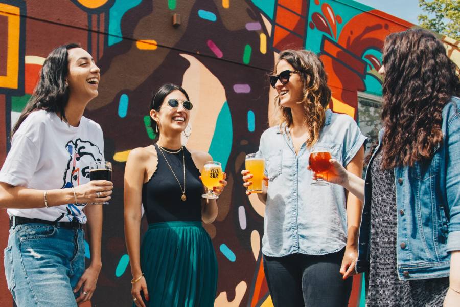 friends hanging outsite having a drink in front of a colorful mural after moving to a new homes in Lockhart TX