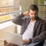 Man using a laptop with a frustrated expression