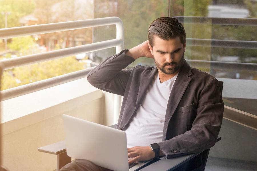 Man using a laptop with a frustrated expression because he is in the middle of buying home realty in Luling TX