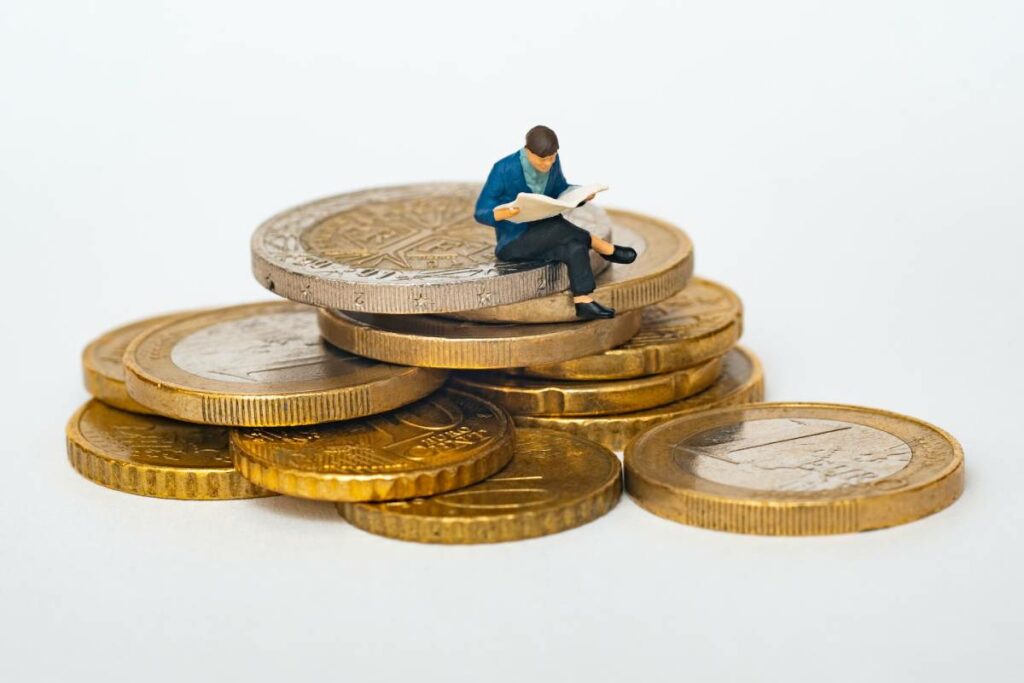 Man enjoying book on top of a pile of coins, representing financial success in new homes Lockhart TX