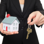 Real estate agent new house keys concept. Realtor showing holding house keys and mini house model.