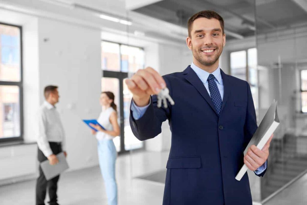 realtor showing the keys of a house and two people talking on the back