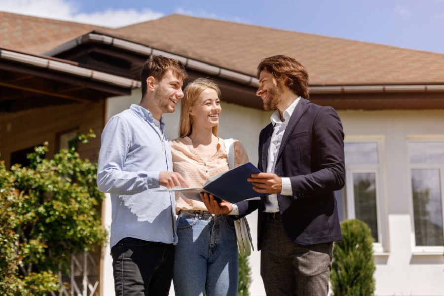 Real estate agent showing home for sell and providing real estate advice to a young couple interested in purchasing a new home