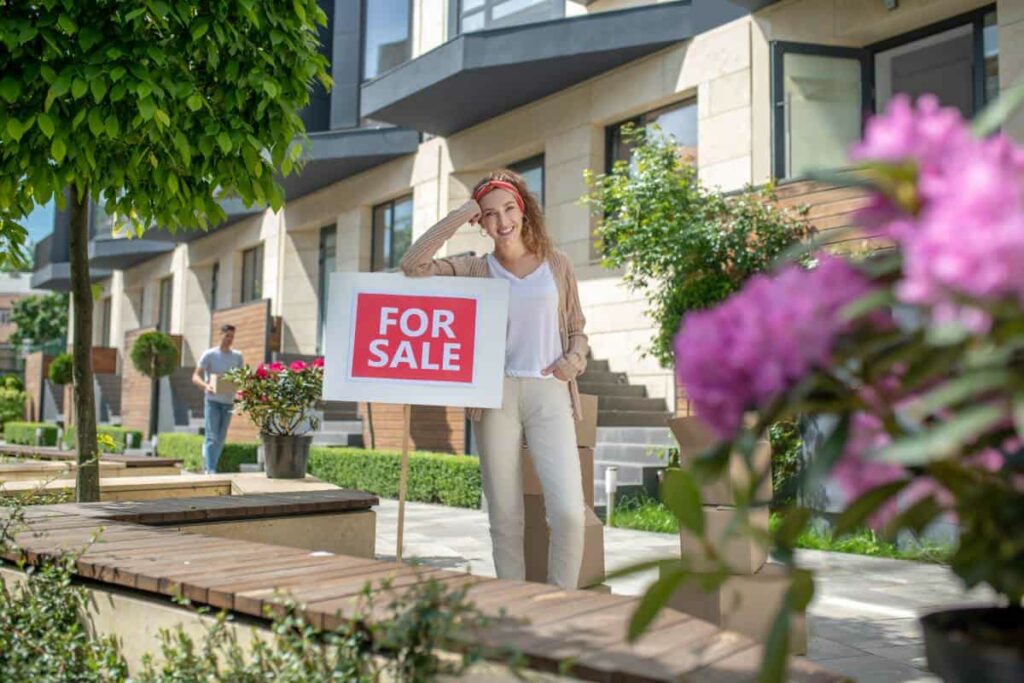 A woman posing next to her Lockhart real estate for sale sign.