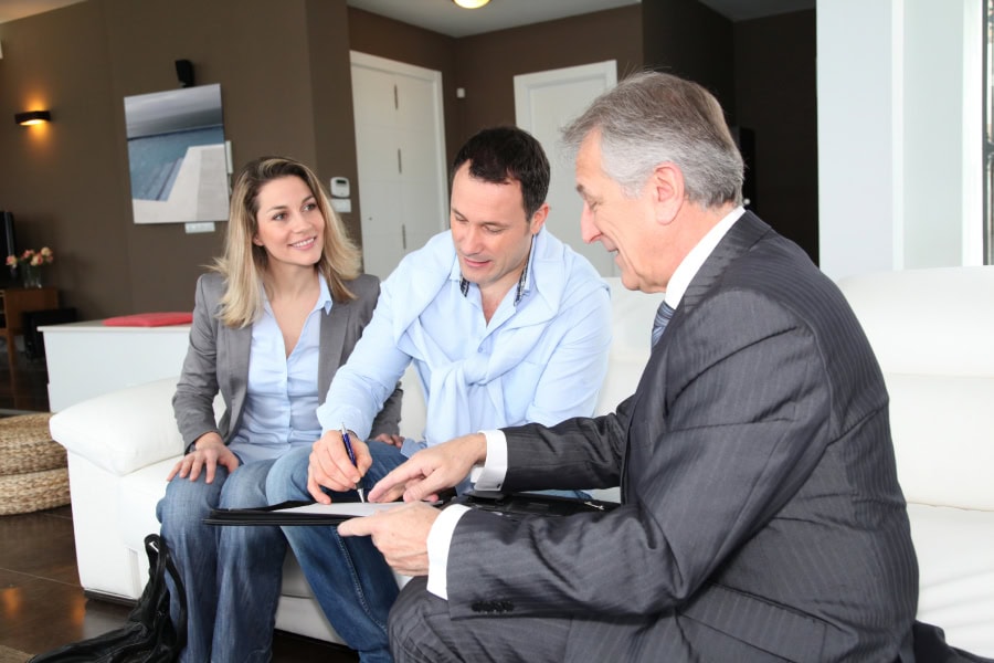 Couple with real-estate agent signing home security investment.