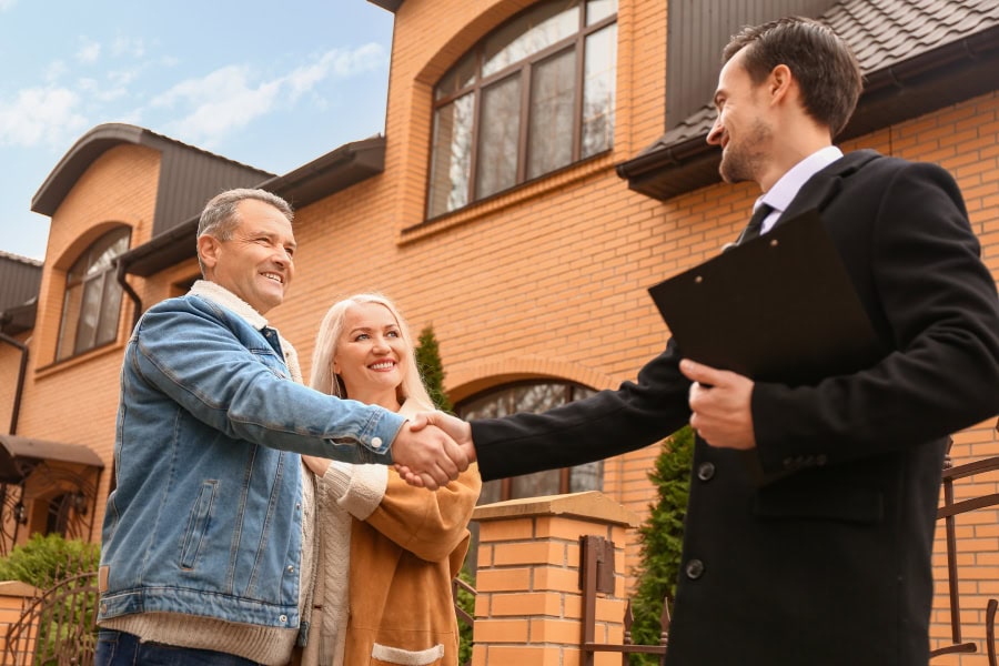 A happy couple shaking hands with realtors in Luling TX after closing on their dream home.