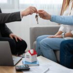 Lockhart realtors handing over house keys to a couple in an office.