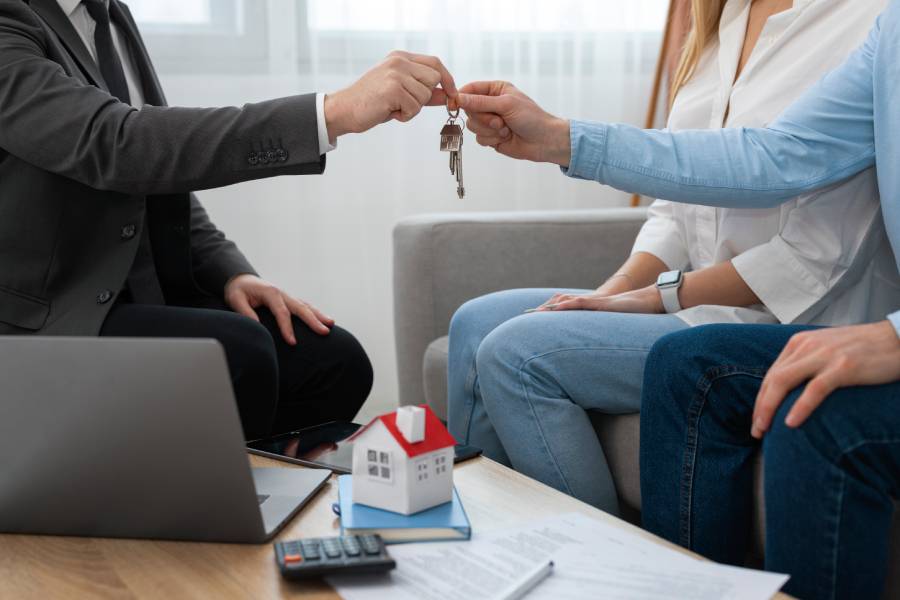 Lockhart realtors handing over house keys to a couple in an office.