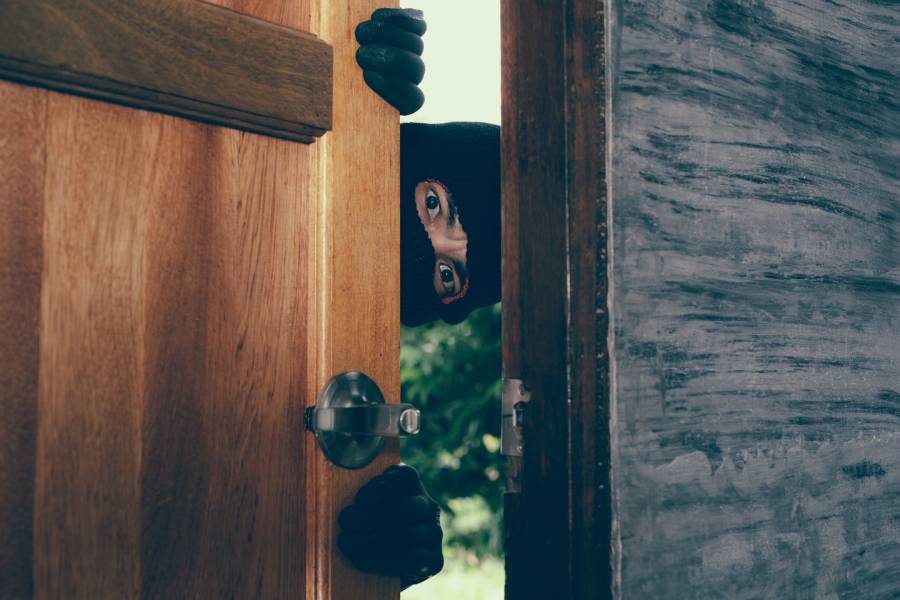 Image of a thief trying to open a house door.