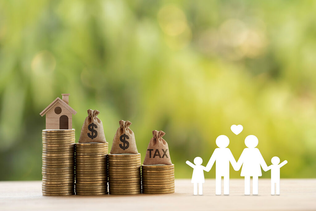 A paper cutout of a family is standing next to a series of steps created by coins with a house at the top.