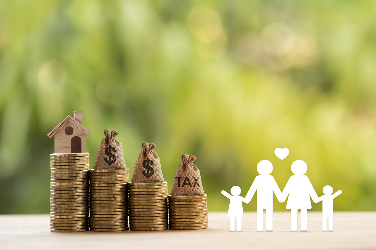 A paper cutout of a family is standing next to a series of steps created by coins with a house at the top.
